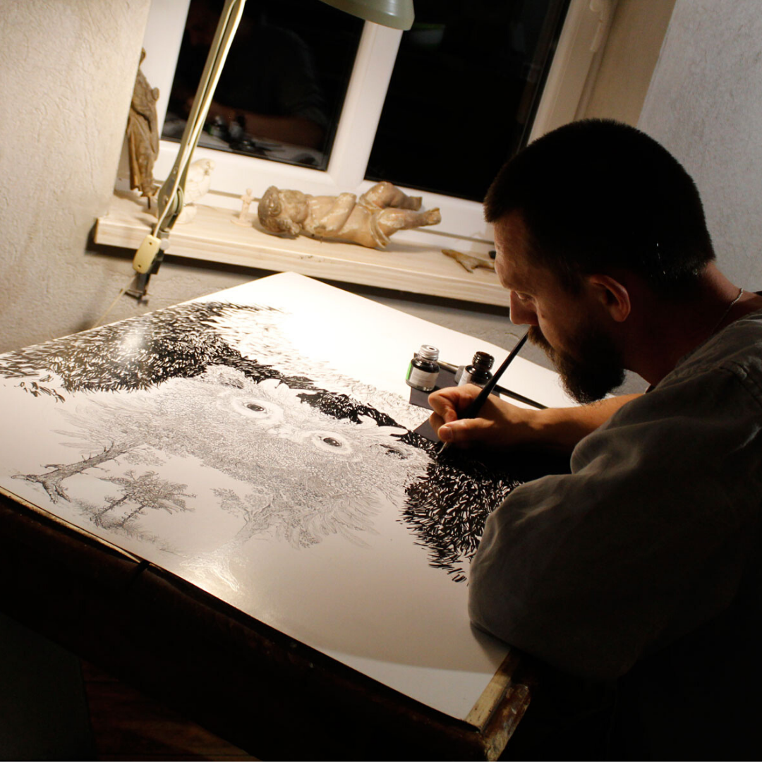 Łukasz Lewandowski z Otwartej Strefy Twórczej rysuje przy biurku